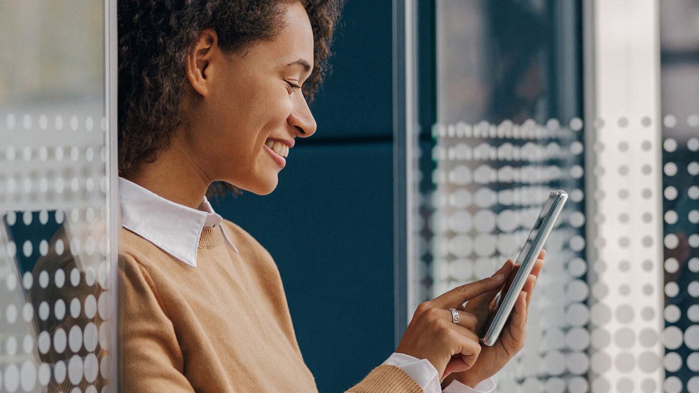 Stylish female freelancer is using mobile phone standing in cowo Stylish female freelancer is using mobile phone standing in cowo